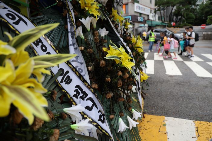 Mourning flowers line the wall of an elementary school in Uijeongbu, Gyeonggi Province, on Aug. 24, 2023. (Yonhap)