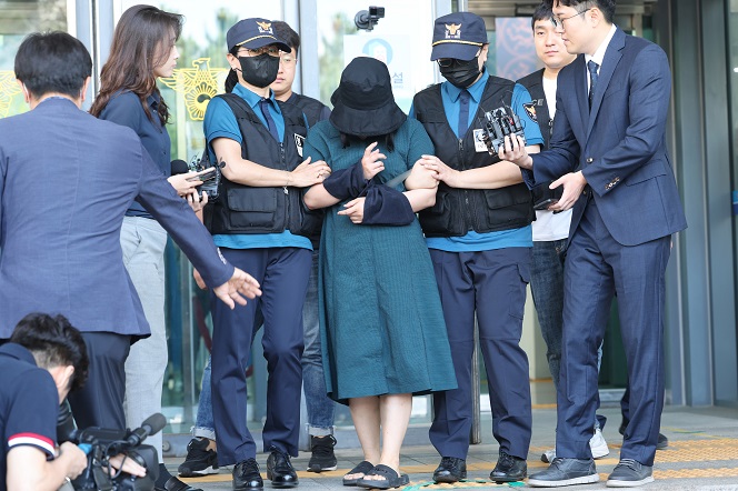 Murder suspect Jung Yoo-jung, wearing a hat and a mask, leaves a police detention center en route to the prosecution in Busan, in this file photo taken June 2, 2023. (Yonhap)