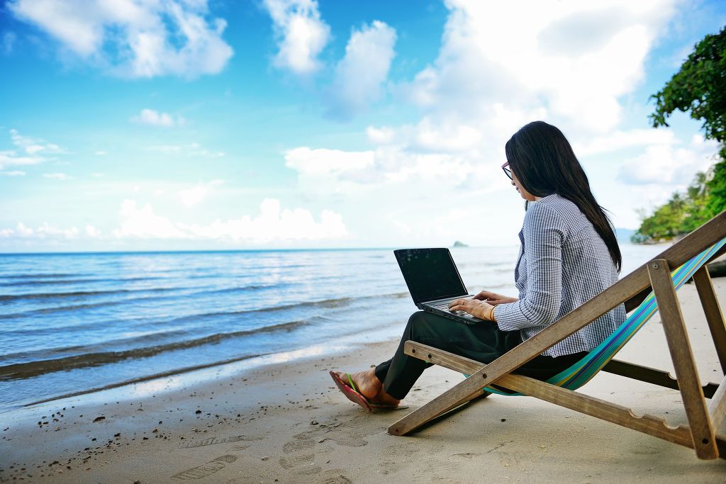 22135812 - business woman using a laptop beside the beach